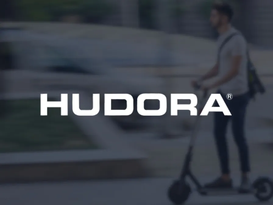 Logo von HUDORA vor dem Foto einer Person auf einem E-Scooter