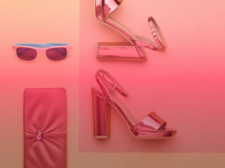 Produktarrangement mit Sonnenbrille, Tasche und Schuhen in Rosatönen