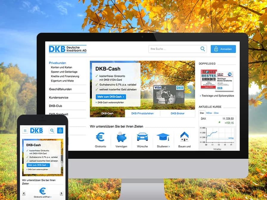 Bildschirm und Smartphone mit der DKB-Website vor einer herbstlichen Landschaft