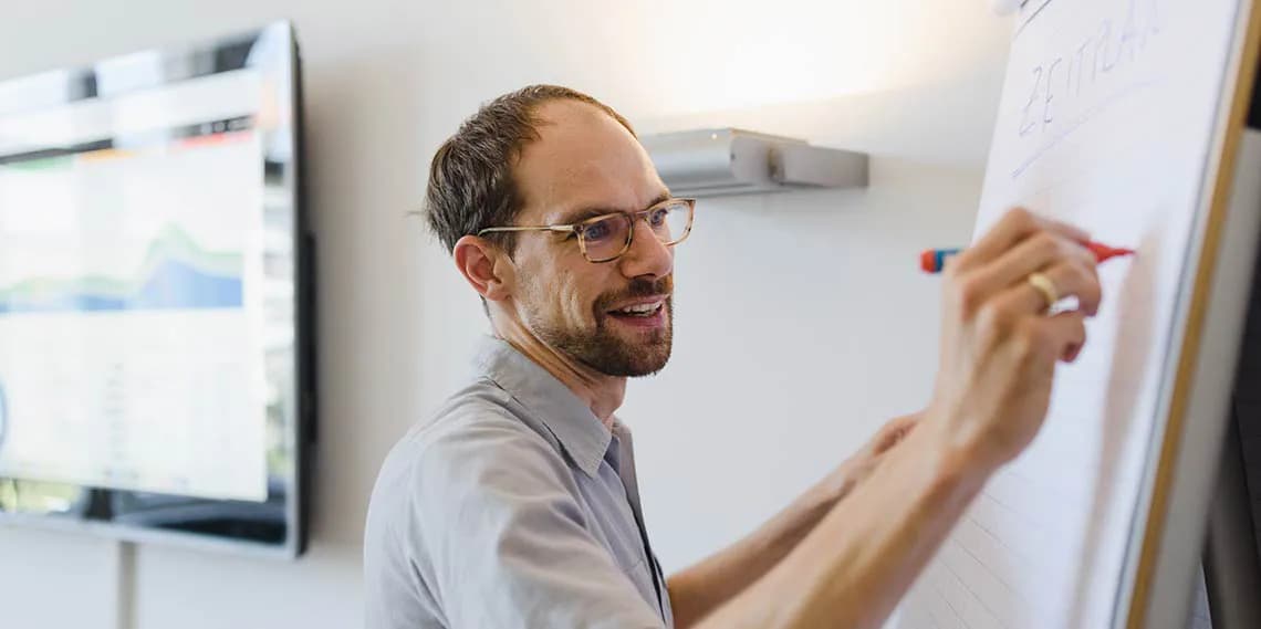 Mitarbeiter schreibt an Flipchart