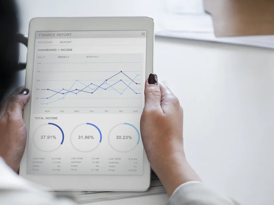 Hände halten ein Tablet mit einem Finanzbericht und Diagrammen