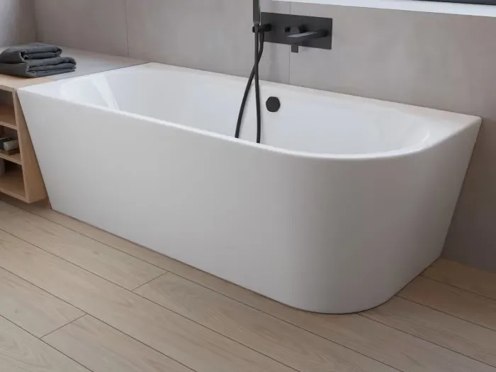 Modernes Badezimmer mit einer eleganten, weißen freistehenden Badewanne, Holzboden und einem Regal mit Handtüchern und Pflegeprodukten neben einem großen Fenster.